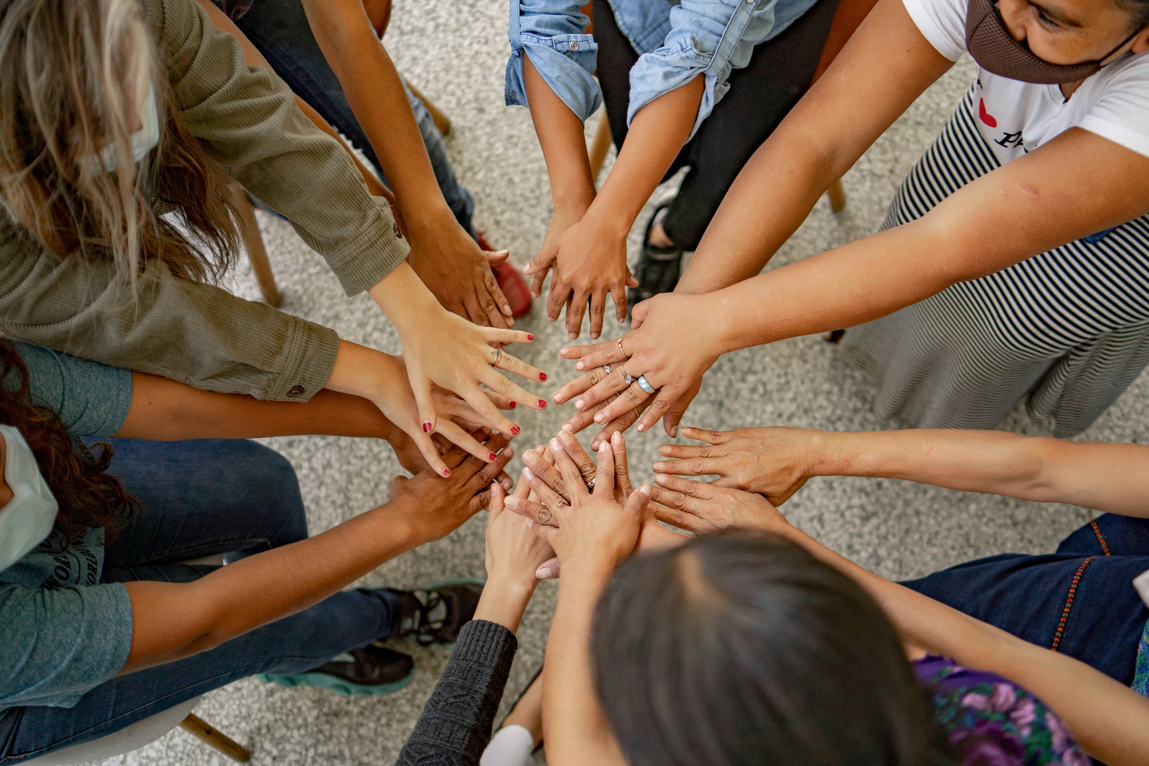 Hero Image - A diverse group of people's hands together in a circle, showing unity and support
